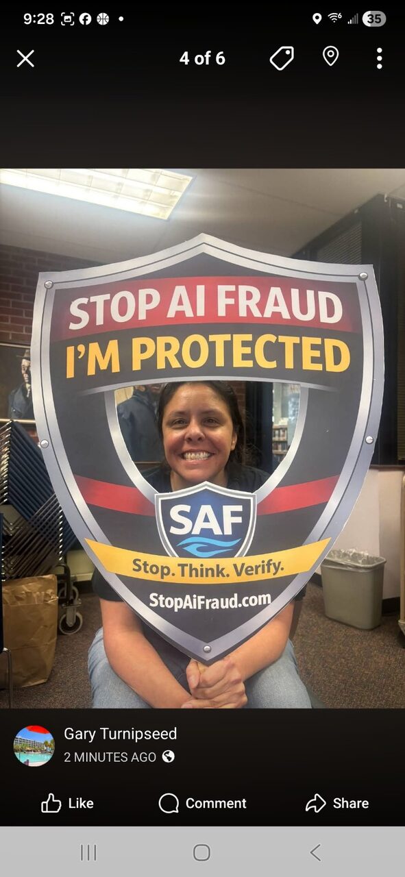 A community member proudly holds the StopAiFraud awareness shield prop after a workshop.